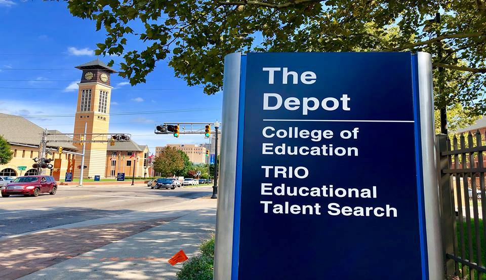 Sign that reads "The Depot - College of Education, TRIO Educational Talent Search" with GVSU clocktower in the background